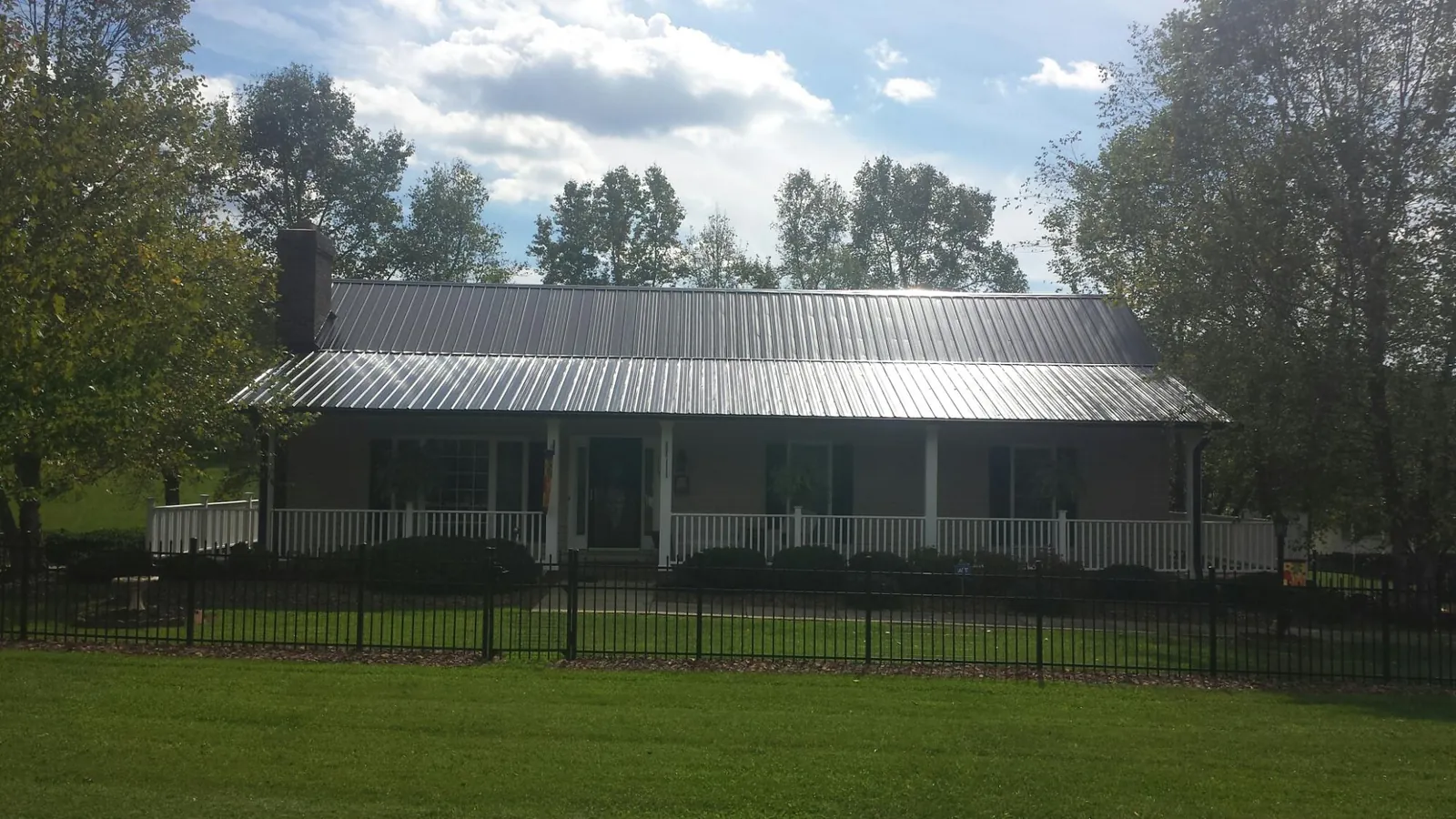 Gray metal roof on a brick ranch with a full width front porch — Gutter Guard Installation work by our crew in Saint Clair