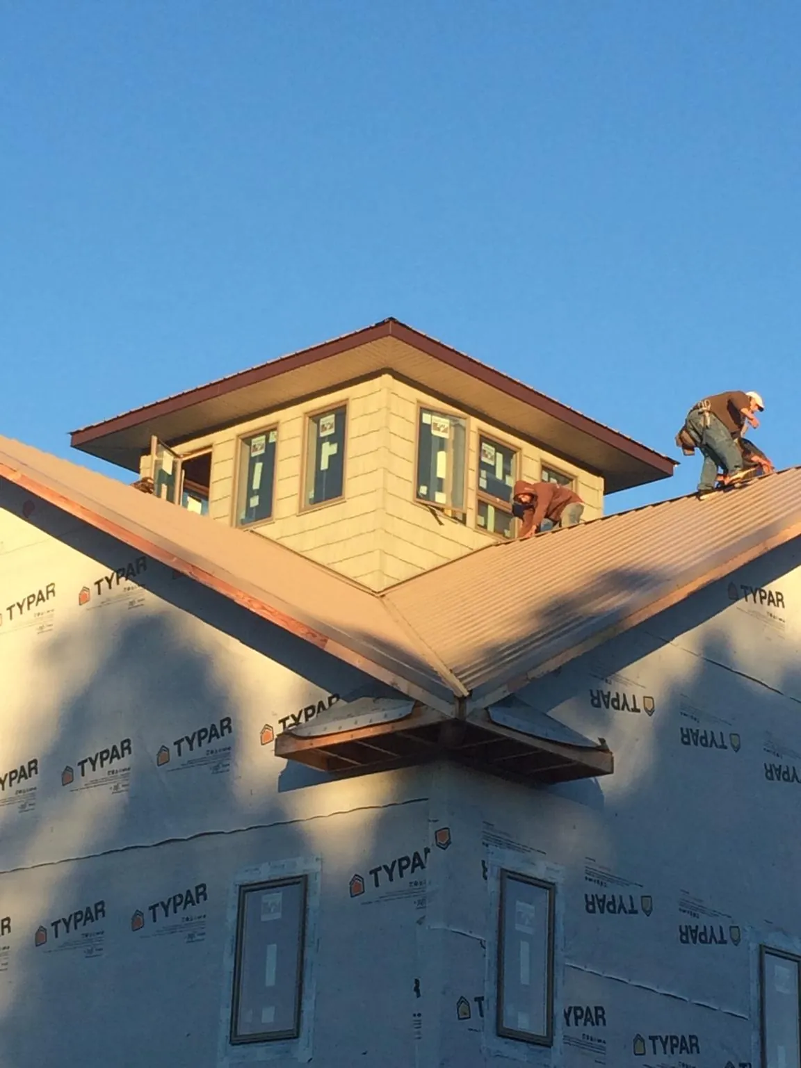 Roofers working around a rooftop cupola on a new metal roof at sunset — Roof Waterproofing in Saint Clair by Roofing Brothers